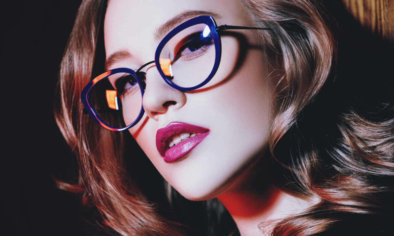 Vrouw met bril Een jonge vrouw met bruin golvend haar en een blauwe bril.